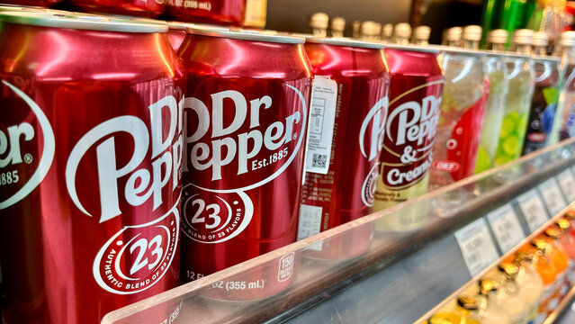 Bali, Indonesia - February, 19, 2026: A close-up image of Dr Pepper cans arranged neatly in a store shelf. The vibrant red color of the cans contrasts with various beverages in the background