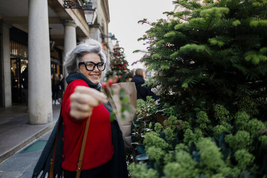 Smiling woman shopping for Christmas holding mistletoe outdoors in London