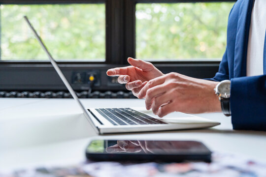 Business person working at office desk on laptop with detail hand close up