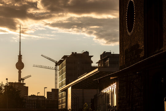Berlin Germany skyline featuring the Fernsehturm tower in sunset silhouette as urban city construction transforms the distant horizon with cranes