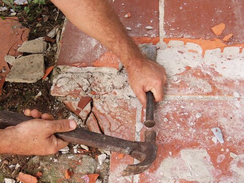 Closeup of man hands holding hammer and steel chisel for breaking up the floor. Working on renovation concept.