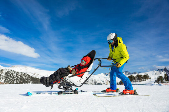 Ski instructor assisting child with adaptive skiing in snowy mountains