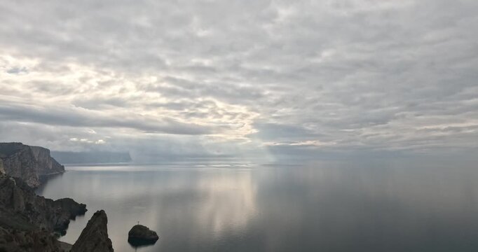Ocean coast cliffs overlook a calm sea under a thick layer of grey clouds creating a moody and atmospheric landscape