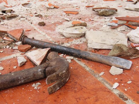 Closeup of hammer and steel chisel used for breaking up the floor. Renovation concept.