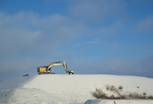 Excavator on snowy dune in the Netherlands on a clear winter day