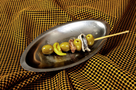 Spanish tapas appetizer with olives and anchovy on metal plate