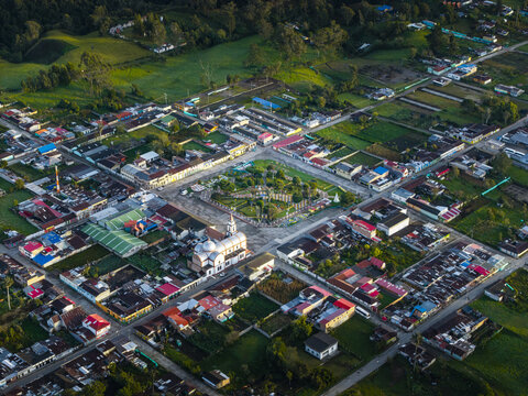 Aerial view of a quaint town nestled amidst verdant landscapes, where the central plaza and church spire stand as focal points, Murillo, Tolima, Colombia.