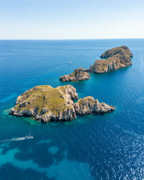Aerial view of rugged islands stand as emerald jewels amidst the turquoise sea, their rocky textures contrasting with the smooth water, Mallorca, Balearic Islands, Spain.