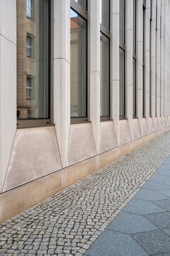 Modern building facade with windows along urban sidewalk in empty perspective revealing pavement space and clean architecture lines for copy background
