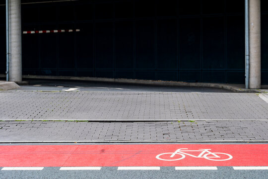 Urban cycleway with bicycle symbol street markings on asphalt near garage entrance creating empty space for city mobility background