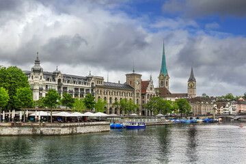 Fototapeta premium Fraumunster and St. Peter churches on the Limmat river bank in Zurich, Switzerland. Historic city buildings and cloudy June sky.