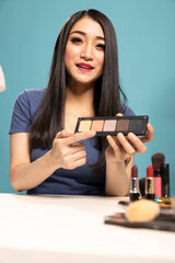 Portrait of female content creator presenting an eyeshadow palette, explaining the different colors...