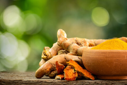 Turmeric or Curcuma longa rhizomes ,dried slices and powder on natural background.