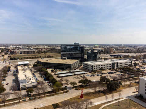 Aerial view of modern buildings casting shadows on the landscape, where glass and concrete meet under a vast sky, Frisco, United States.