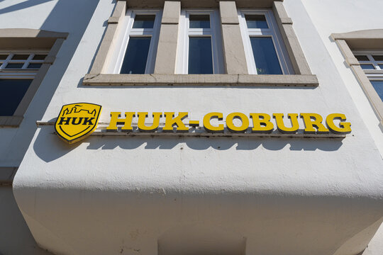 Neuss, Germany - September 6 2025: HUK insurance logo sign mounted on building wall along urban street in Neuss, Germany
