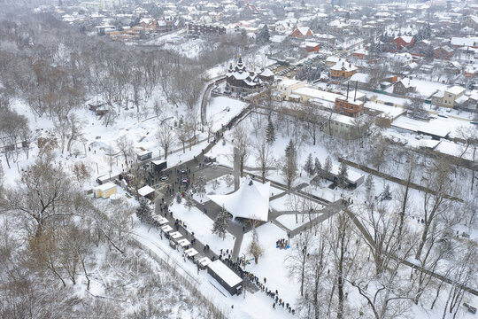 Aerial view of people gathering at the snow-laden Holy Intercession Monastery, a beacon of light amidst the muted winter landscape, Kharkiv, Kharkiv Oblast, Ukraine.