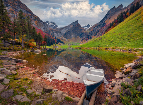 Incredible autumn scene of Swiss Alps with Santis peak reflected in calm waters of Seealpsee lake. Attractive outdoor scene of white fishing boat on the lake, Switzerland.