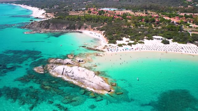 4K Aerial View of Scoglio di Peppino Rock in Costa Rei Sardinia. Cinematic Drone Flight over Granite Boulder, Turquoise Sea and White Sandy Beach. Tropical Mediterranean Landscape Italy.