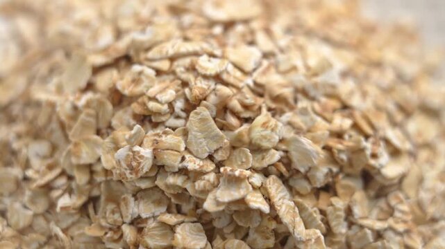 Uncooked oat flakes forming natural whole grain cereal layer. Dry plant based food. Healthy lifestyle meals ingredient. Macro. Rotation