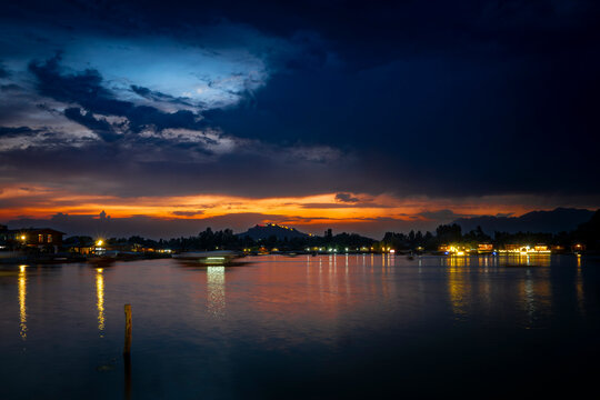 Panoramic sunset view of Dal Lake with illuminated houseboats and Hari Parbat Fort, Srinagar, Kashmir