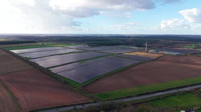 Cinematic drone shot of renewable energy generation at a British agrivoltaic farm with solar panels and green cultivated land