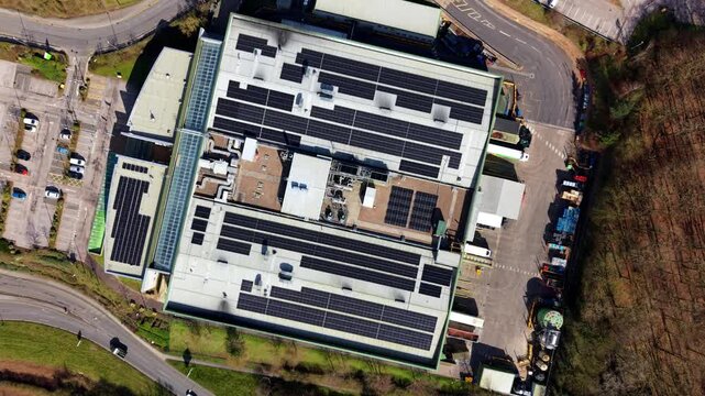 Top down aerial view of a large industrial warehouse rooftop with solar panel arrays and HVAC cooling systems in Nottingham UK