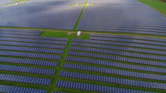 Cinematic drone shot of renewable energy generation at a British agrivoltaic farm with solar panels and green cultivated land