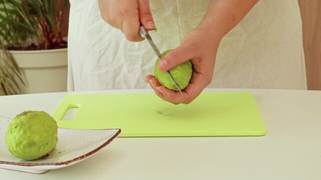 Female hands cutting and peeling fresh green avocado fruit