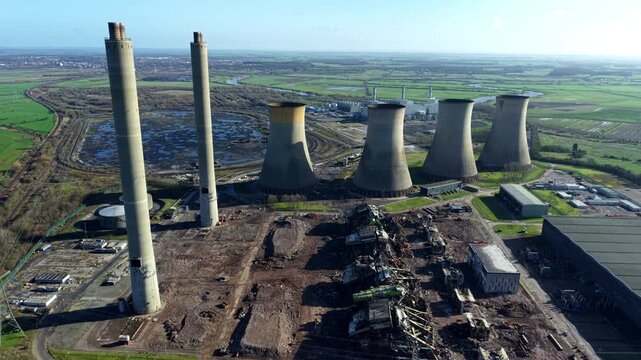 Aerial drone view of decommissioned West Burton power station cooling towers and chimneys under active demolition process in Nottinghamshire UK.