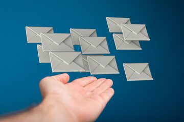 Concept of email marketing, communication and sending messages. Hand with floating envelopes on a...