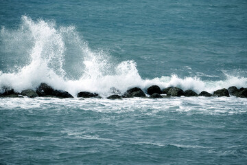 Obraz premium Powerful sea waves crashing on rocks as on breakwater and making lot of white splashes