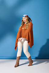 Fototapeta premium Graceful young woman exuding charm in a stylish outfit against a vibrant blue background