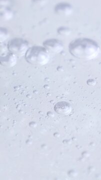 Transparent cosmetic liquid gel with bubbles flowing close up, vertical video format