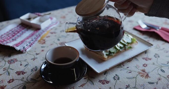 Close up of person serving a tea during breakfast with sandwich