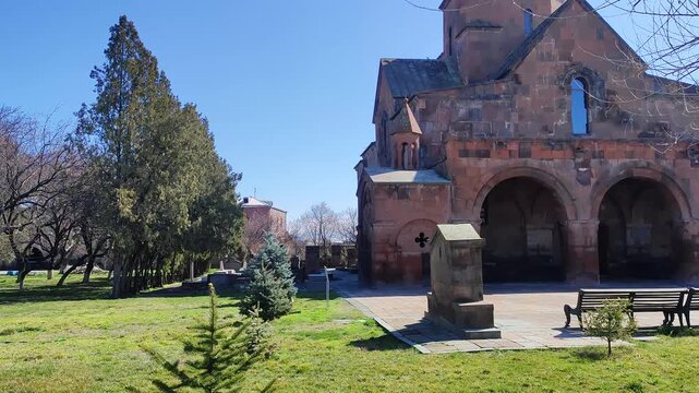 Saint Gayane Monastery, surrounded by a lush green park with trees and benches under a clear blue sky