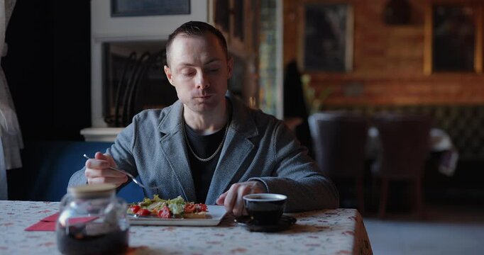Handsome man in jacket sitting at the table with delicious lunch in a restaurant