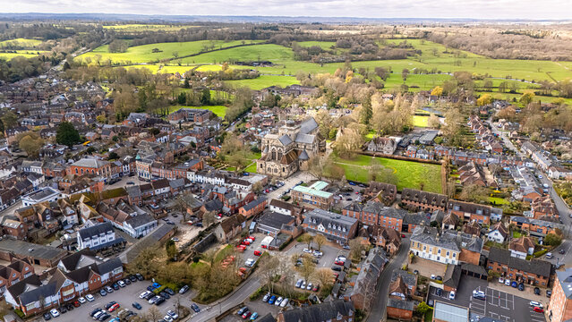 Landscape shot of Romsey, Hampshire with lush green vibrant fields in distance and overcast sunny spring skies at sunset with calm quiet roads below