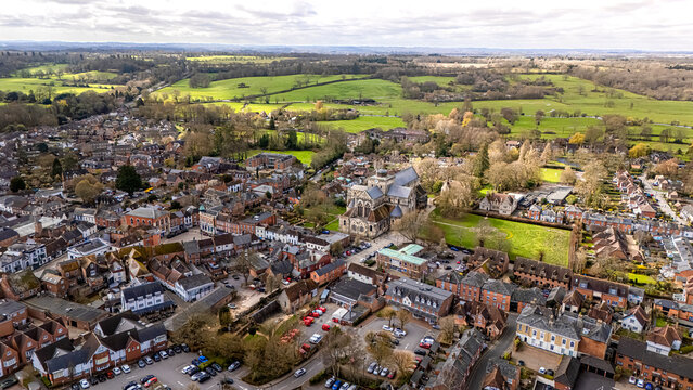 Landscape shot of Romsey, Hampshire with lush green vibrant fields in distance and overcast sunny spring skies at sunset with calm quiet roads below