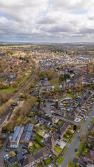Fototapeta premium Portrait aerial drone shot overlooking Romsey, Hampshire with residential housing and railway track around quiet roads on overcast sunny spring day