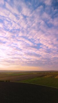 Forward drone flight over plowed farmland under dramatic cloud sky. Forward aerial movement above freshly plowed agricultural land with textured soil patterns and scenic cloudy sky