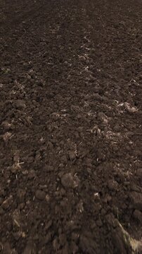 Low forward drone flight over freshly plowed agricultural soil. Low altitude drone flight moving forward above textured plowed soil creating dynamic agricultural pattern and rural farming concept.