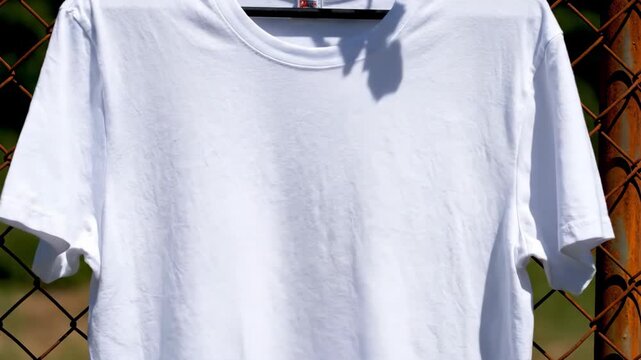 Close Up White T Shirt Mockup Hanging on Rusty Chain Link Fence Animation