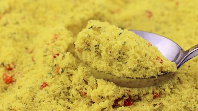 Yellow chicken stock powder seasoning taking with a spoon close up