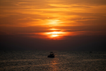 Fototapeta premium Boat silhoutted against the orange sky