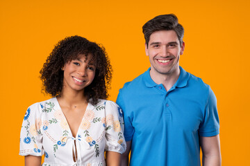 Fototapeta premium Happy Young Couple Smiling At Camera Standing Together On Yellow Studio Backdrop