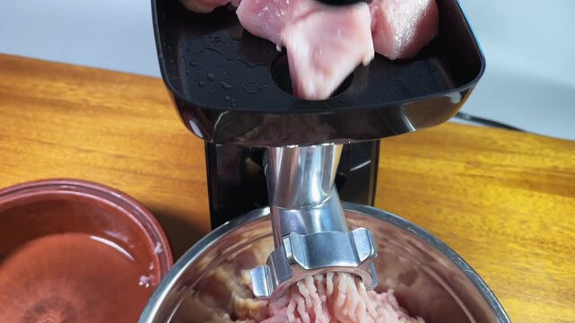 Grinding poultry meat into ground meat with electric meat grinder