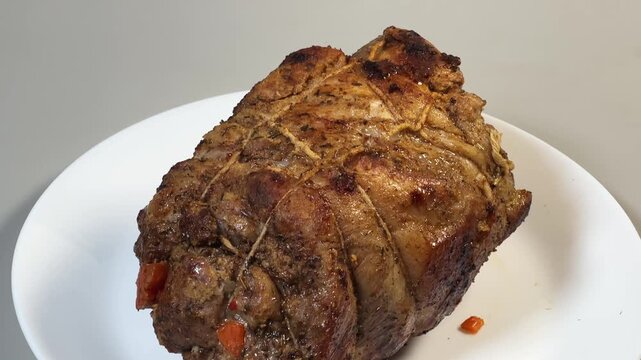 Baked pork neck with spices tied with twine on plate