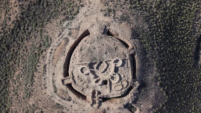 Top-down aerial shot of the circular Neolithic fortress at Los Millares in southern Spain. The drone captures the concentric stone walls, burial mounds, and fortified layout of this ancient archaeolog