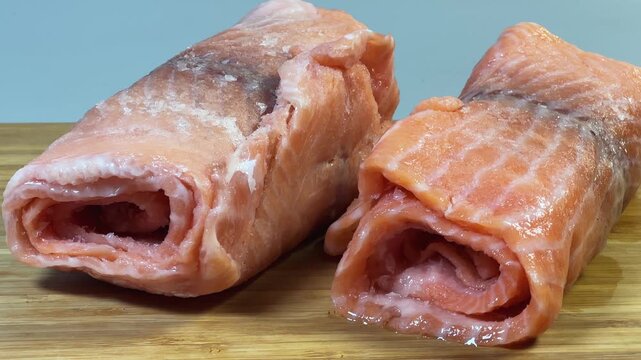 Raw frozen slices of salmon rolled up on cutting board