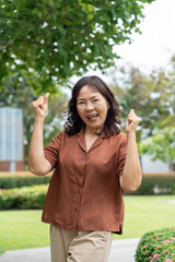 Fototapeta premium Portrait of smiling pretty senior asian woman 60 years old with urban natural park background, happy retirement lady with healthy aging in life security protection insurance for future planning.